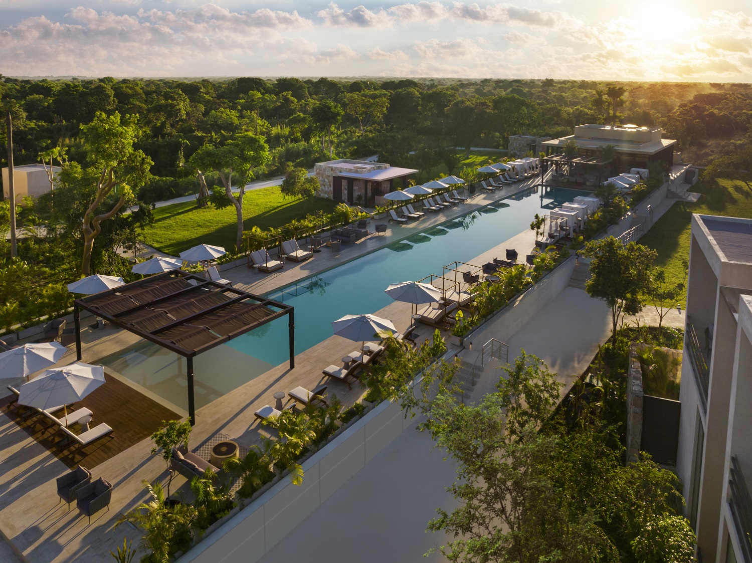 A serene pool with loungers and umbrellas at Hacienda Xcanatun, Angsana Heritage Collection, surrounded by lush greenery.